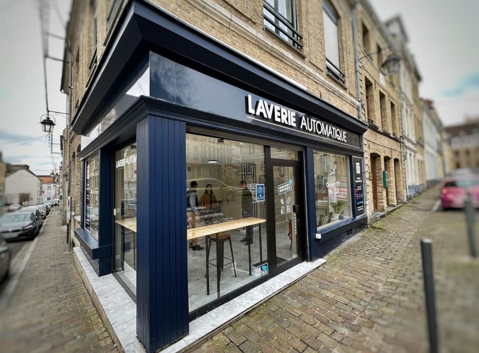 featured_Laverie de Saint Omer A laundry shop front with a vibrant blue door and expansive windows, enhancing its appeal to passersby.